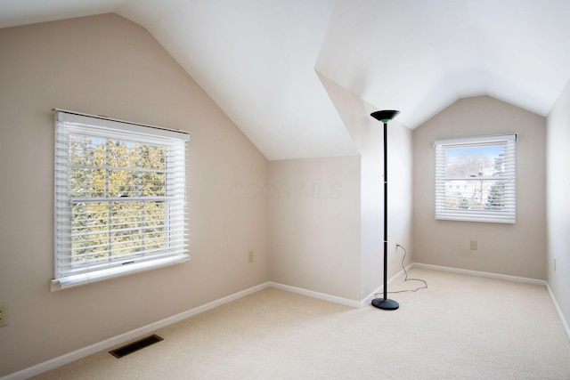 bonus room featuring light colored carpet, visible vents, vaulted ceiling, and baseboards