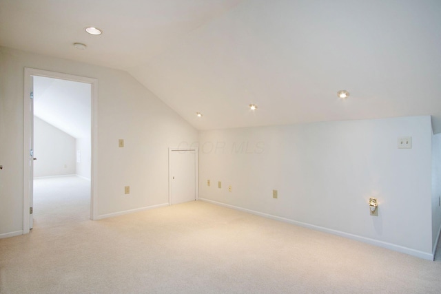 additional living space with light carpet, vaulted ceiling, and baseboards