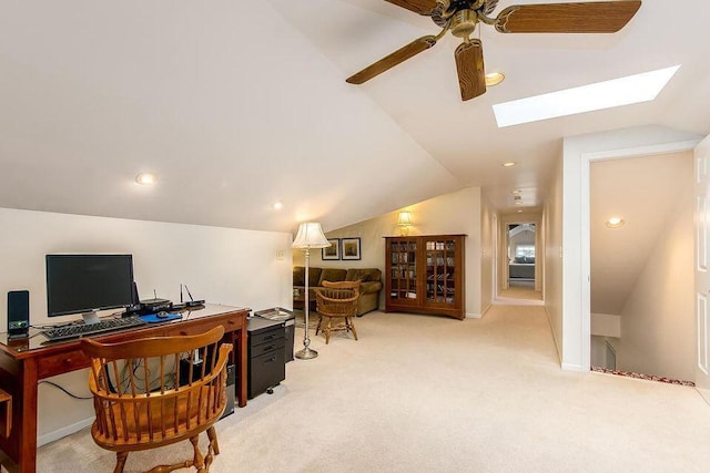 home office featuring ceiling fan, lofted ceiling with skylight, baseboards, and light colored carpet