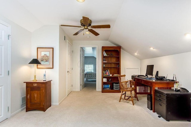 office space with vaulted ceiling, ceiling fan, baseboards, and light colored carpet