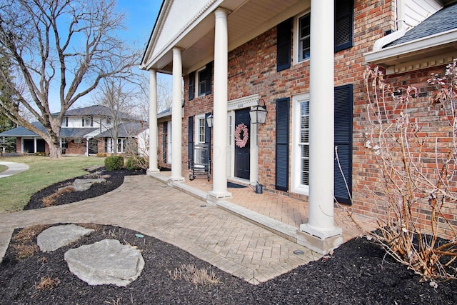 exterior space featuring brick siding and roof with shingles