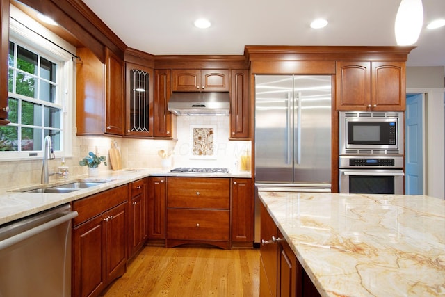 4580 Helston Ct, Columbus, OH 43220 - kitchen featuring built in appliances, under cabinet range hood, a sink, light wood-style floors, and light stone counters
