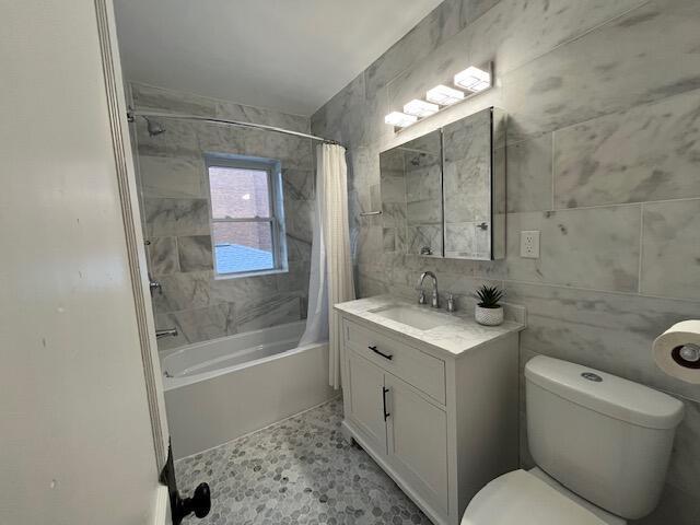 full bathroom featuring toilet, shower / bath combo, tile patterned flooring, tile walls, and vanity