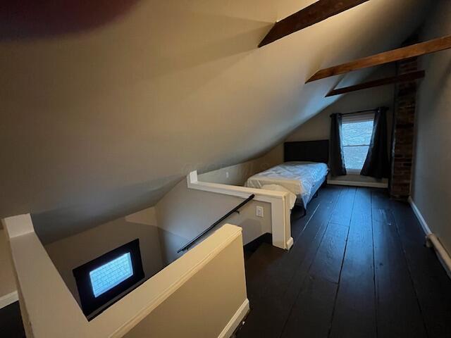 bedroom with dark wood-type flooring and lofted ceiling with beams