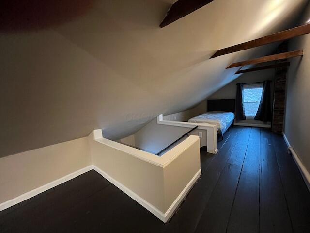 unfurnished bedroom featuring lofted ceiling and dark hardwood / wood-style floors