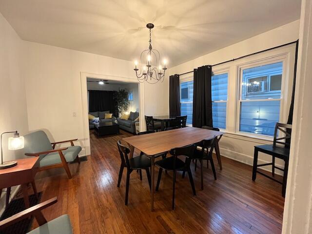 dining area featuring dark wood-type flooring and a notable chandelier