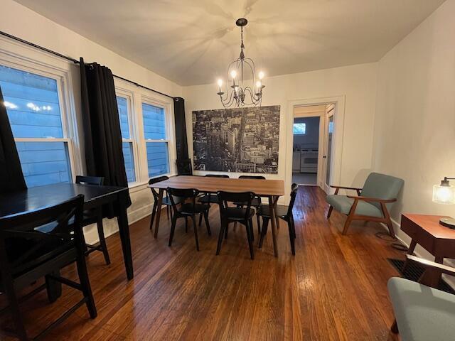 dining area with dark wood-type flooring and an inviting chandelier