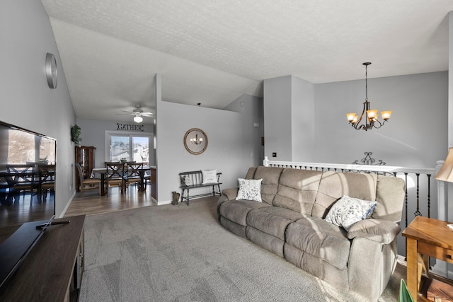 carpeted living room featuring ceiling fan with notable chandelier, a textured ceiling, and vaulted ceiling