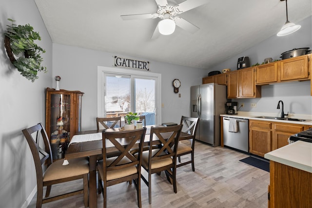 kitchen featuring stainless steel appliances, light wood-type flooring, vaulted ceiling, pendant lighting, and sink