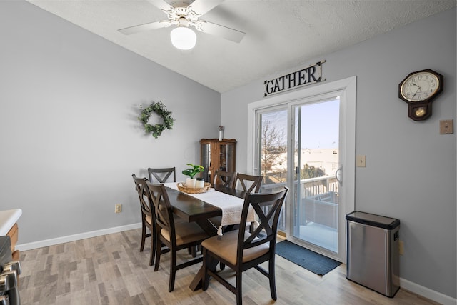 dining space featuring ceiling fan, light wood-type flooring, and a textured ceiling