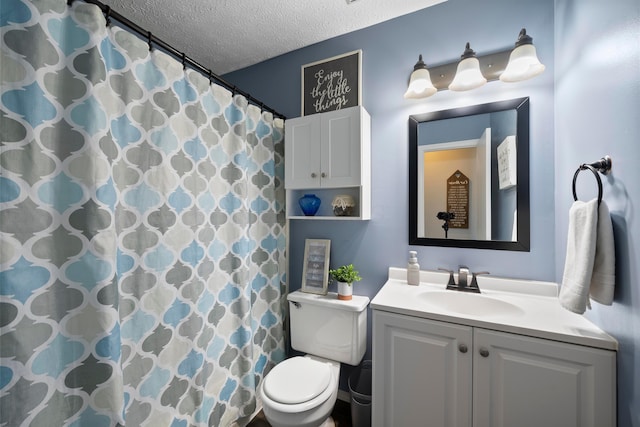 bathroom featuring toilet, vanity, a shower with curtain, and a textured ceiling