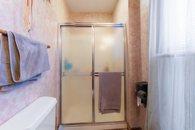 bathroom featuring toilet and a shower with door