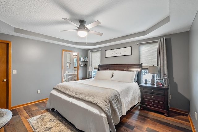 bedroom featuring a raised ceiling, ceiling fan, and dark wood-type flooring