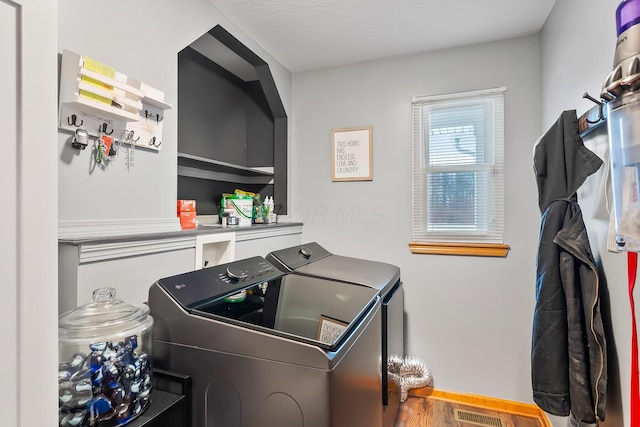 washroom with washing machine and dryer and hardwood / wood-style flooring