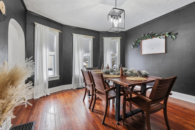 dining room featuring wood-type flooring, a notable chandelier, ornamental molding, and a textured ceiling