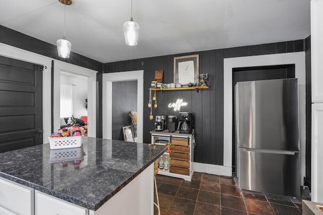 kitchen featuring white cabinetry, pendant lighting, dark stone countertops, and stainless steel fridge