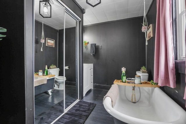 bathroom featuring toilet, vanity, and a tub to relax in