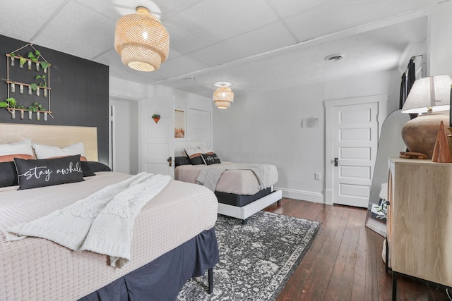 bedroom featuring a drop ceiling and dark hardwood / wood-style floors