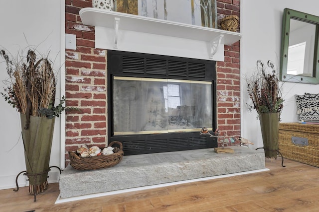 details with a brick fireplace and wood-type flooring