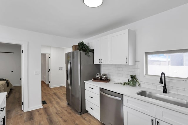 kitchen with tasteful backsplash, white cabinets, sink, dark wood-type flooring, and stainless steel appliances