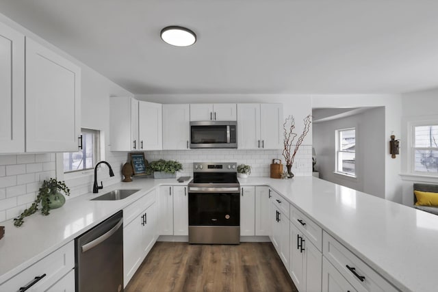 kitchen with sink, appliances with stainless steel finishes, dark hardwood / wood-style floors, white cabinets, and decorative backsplash