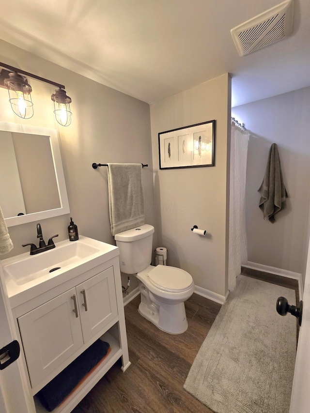 bathroom with toilet, hardwood / wood-style flooring, and vanity