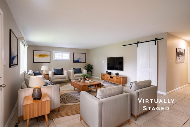 living room with light tile patterned floors, a barn door, and baseboards