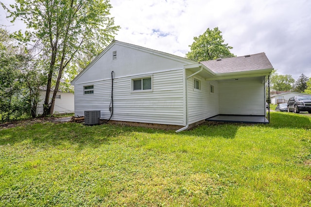back of house with central air condition unit and a yard