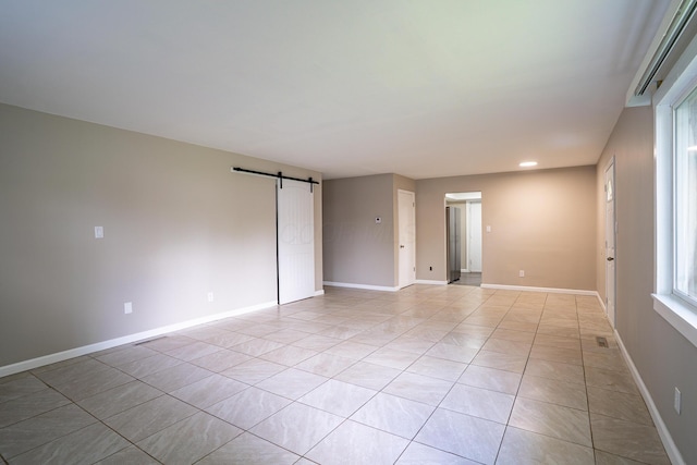 spare room with baseboards, recessed lighting, a barn door, and light tile patterned flooring