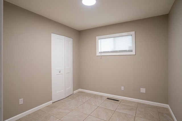 unfurnished bedroom with baseboards, a closet, visible vents, and light tile patterned flooring