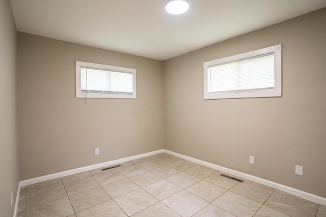 spare room with baseboards, light tile patterned floors, and visible vents