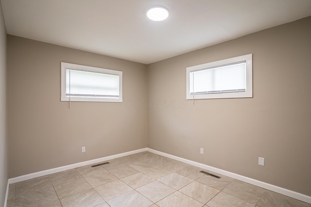 spare room with a wealth of natural light, visible vents, and baseboards