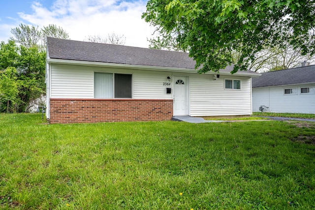ranch-style home featuring a front yard, roof with shingles, and brick siding