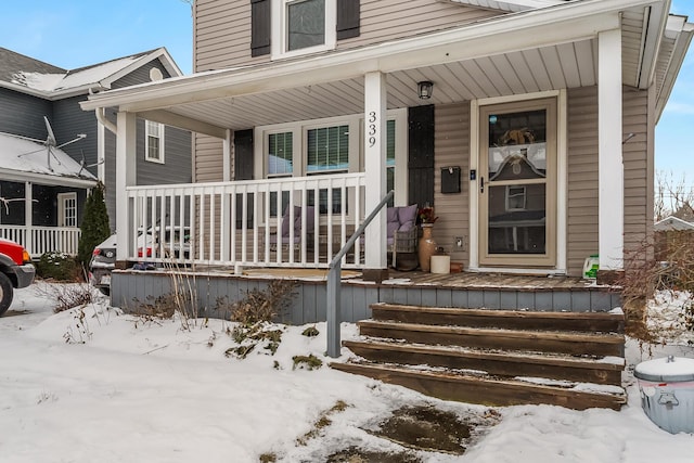 snow covered property entrance with a porch