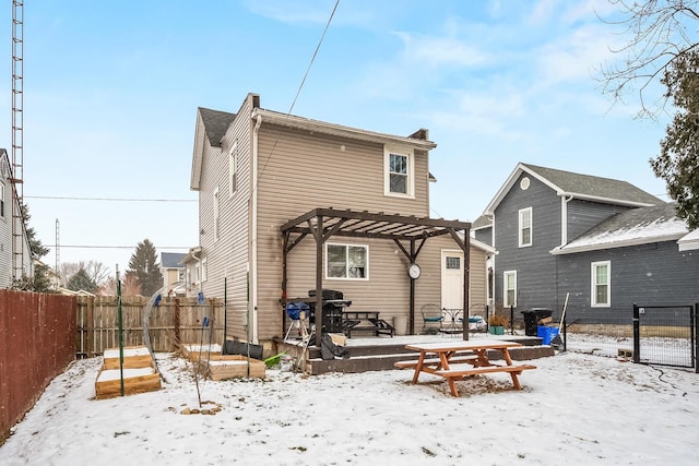 snow covered back of property featuring a pergola and a wooden deck