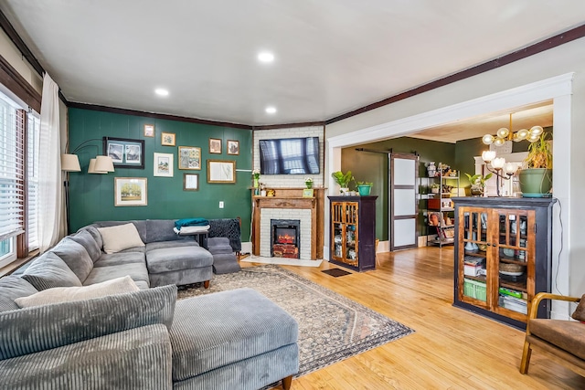 living room featuring wood-type flooring, a fireplace, an inviting chandelier, and ornamental molding