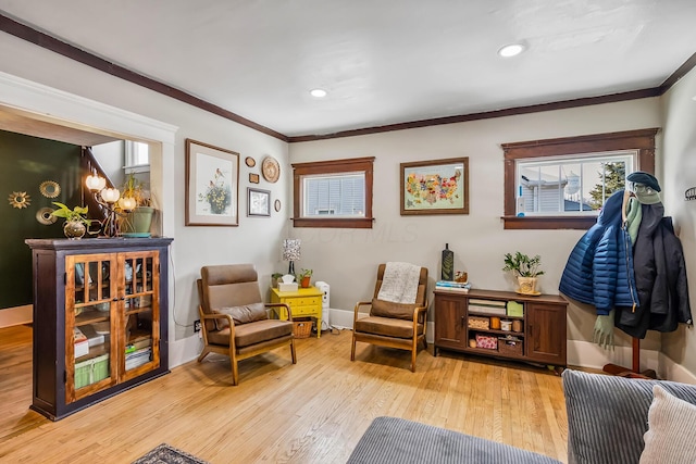 sitting room with crown molding and light hardwood / wood-style floors