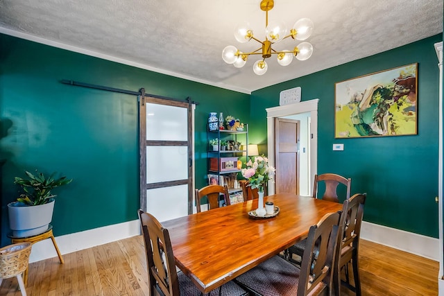 dining room with a textured ceiling, light hardwood / wood-style flooring, a barn door, and a notable chandelier