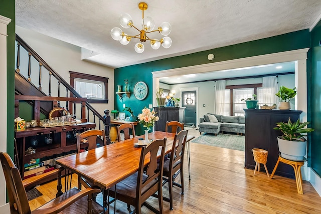 dining room with light wood-type flooring, an inviting chandelier, and a textured ceiling