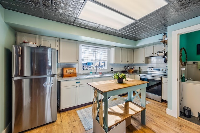 kitchen with backsplash, sink, stainless steel appliances, and light hardwood / wood-style flooring