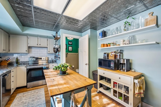 kitchen featuring backsplash, appliances with stainless steel finishes, and light hardwood / wood-style floors