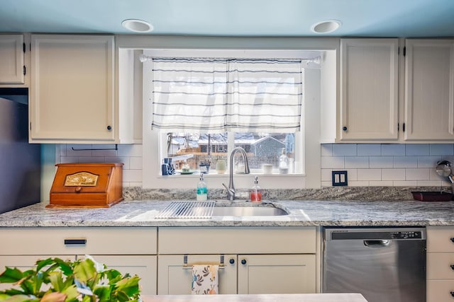 kitchen featuring white cabinets, stainless steel dishwasher, tasteful backsplash, and sink