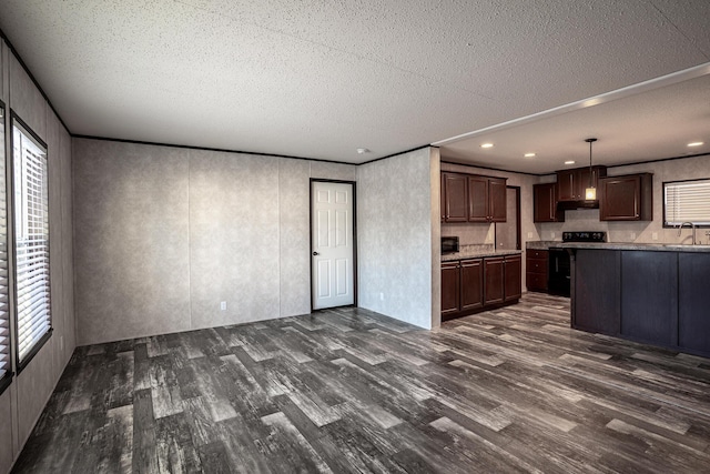 kitchen with pendant lighting, dark wood-type flooring, black / electric stove, sink, and dark brown cabinets