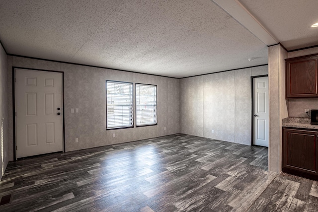 unfurnished living room featuring dark wood-type flooring, a textured ceiling, and ornamental molding