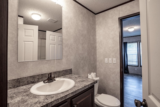 bathroom with a textured ceiling, crown molding, wood-type flooring, and vanity