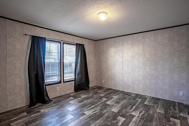 empty room featuring dark wood-type flooring, a textured ceiling, and crown molding