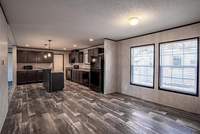 kitchen featuring decorative light fixtures, dark hardwood / wood-style flooring, dark brown cabinets, a kitchen island, and black appliances