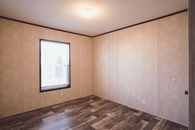 empty room featuring dark wood-type flooring, a textured ceiling, and ornamental molding