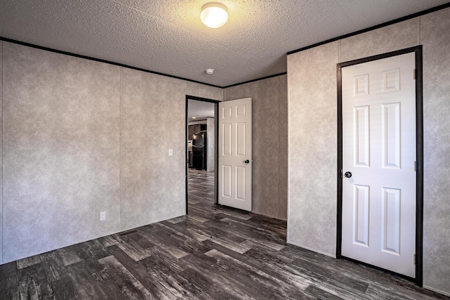 unfurnished bedroom featuring a textured ceiling, crown molding, and dark hardwood / wood-style floors