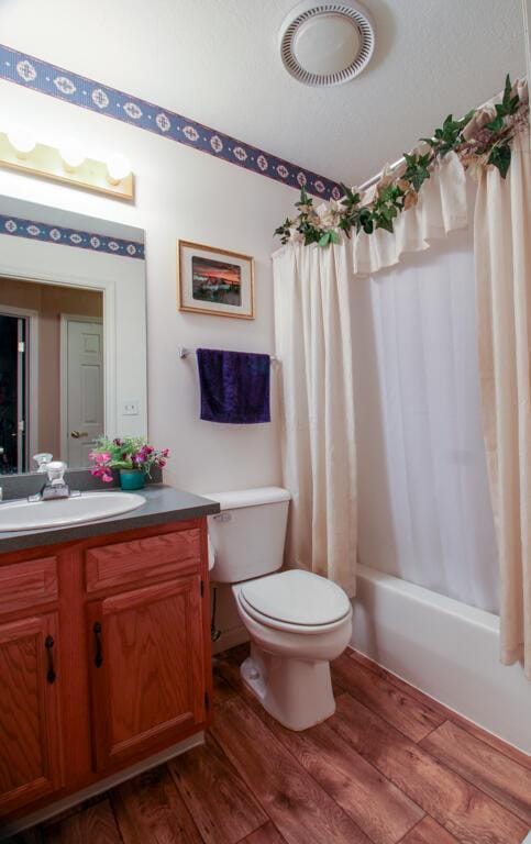 full bathroom featuring wood-type flooring, toilet, vanity, and shower / bath combination with curtain